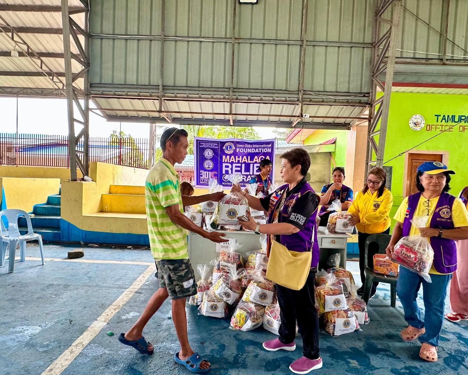A Lion handing a relief pack to a community member